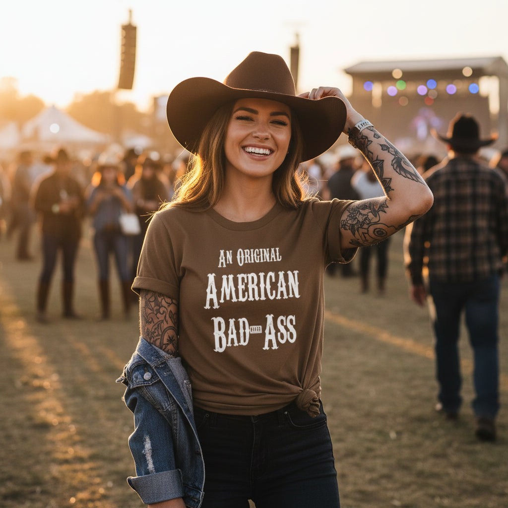 Brown t-shirt with 'An Original American Bad Ass' text in a barn setting.