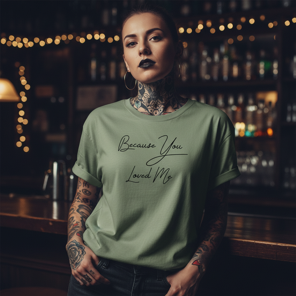 Green t-shirt with 'Because You Loved Me' text on a white background