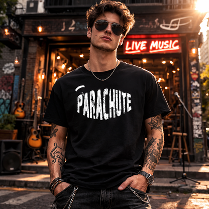 Man wearing a black 'Parachute' t-shirt in front of a live music venue.