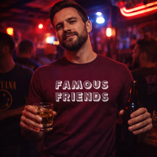 Man in a bar wearing a 'Famous Friends' shirt holding a drink.