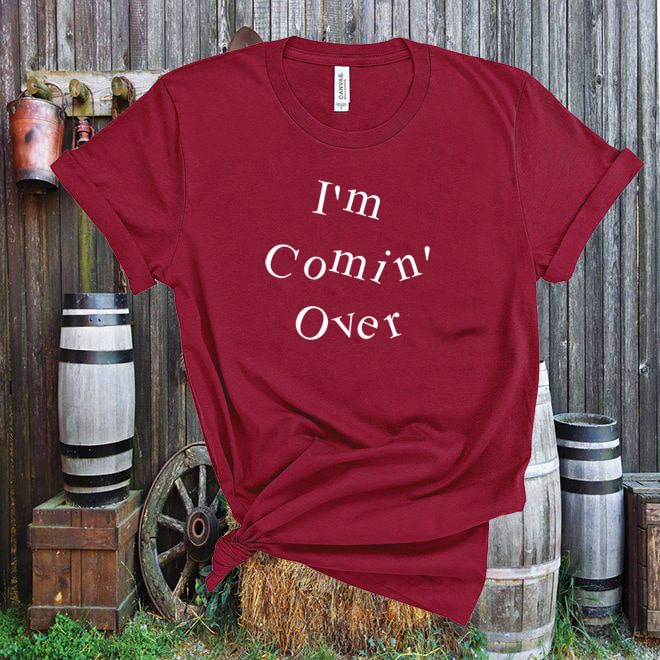 Red t-shirt with 'I'm Comin' Over' text against a rustic wooden background.