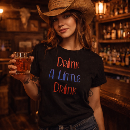 Woman in a bar wearing a black t-shirt with colorful text and a cowboy hat, holding a glass of beer.