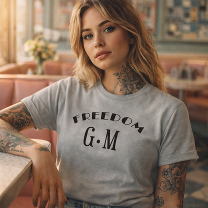 Woman wearing a gray t-shirt with 'FREEDOM G.M' text in a casual setting.
