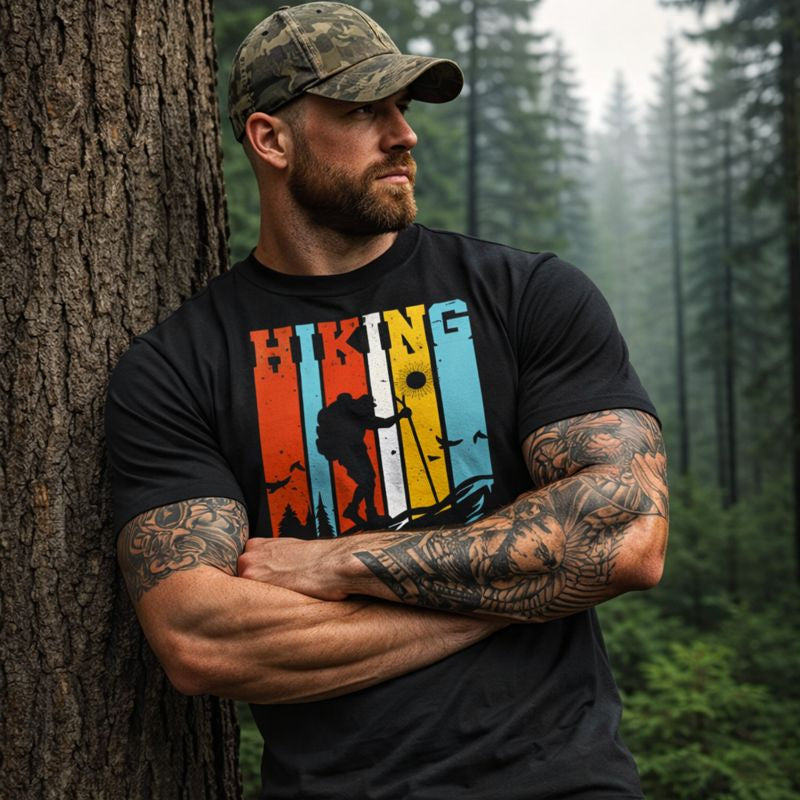 Man wearing a black t-shirt with 'Hiking' design leaning against a tree in a forest.
