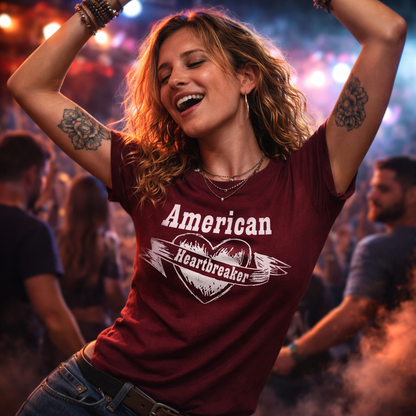 Woman wearing a 'American Heartbreaker' t-shirt at a concert with arms raised.