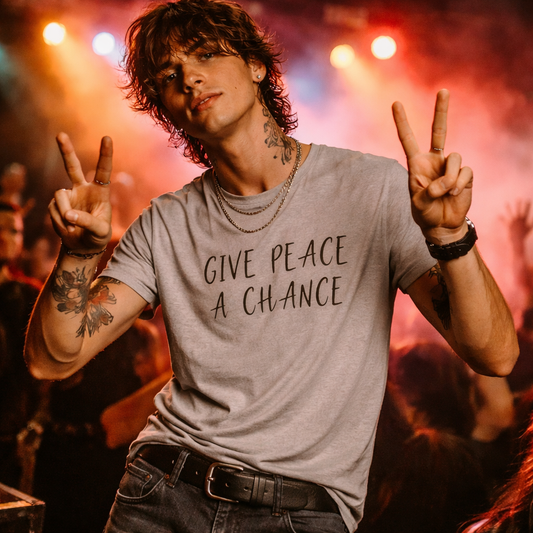 Person wearing a t-shirt with 'Give Peace a Chance' on stage with red lights and smoke.