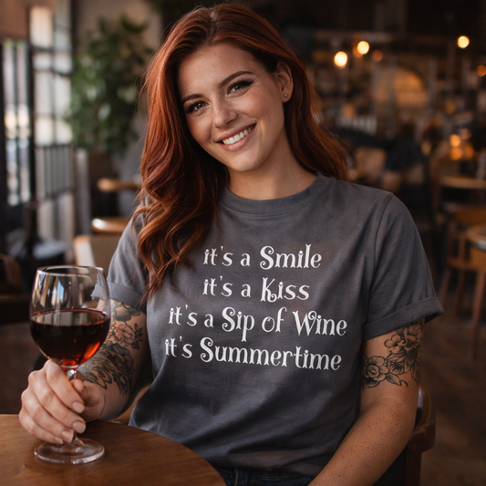 Woman in a casual setting holding a glass of wine, wearing a t-shirt with a summertime quote.