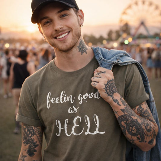 Man wearing a t-shirt with 'feelin good as HELL' text at a festival.
