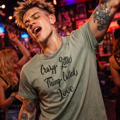 Person wearing a t-shirt with 'Crazy Little Thing Called Love' in a lively bar setting