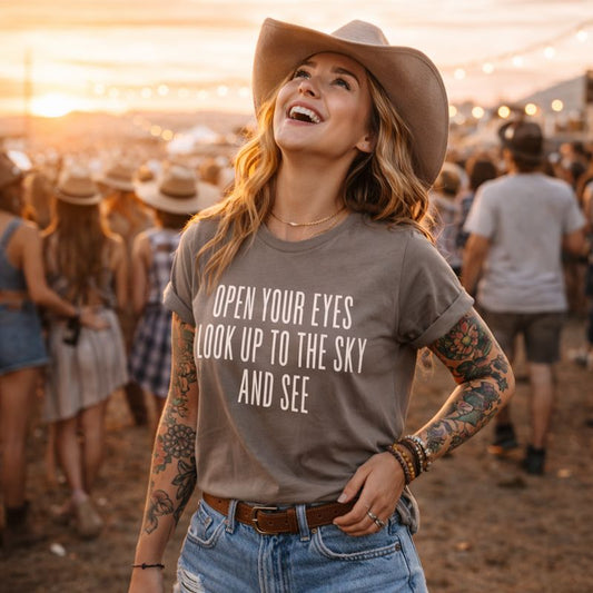 Woman wearing a cowboy hat and t-shirt with a motivational quote at a music festival.