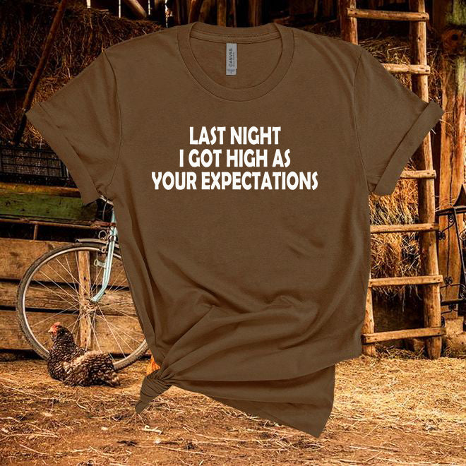 Brown t-shirt with text 'Last night I got high as your expectations' in a rustic setting with a chicken and bicycle.