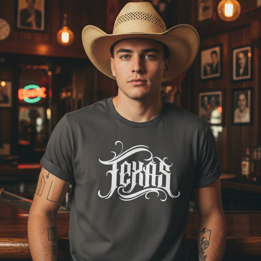 Gray t-shirt with 'Texas' printed on it, placed on a woven basket with a hat in the background.
