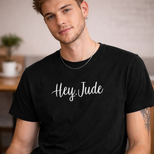 Man wearing a black t-shirt with 'Hey Jude' text in a casual setting