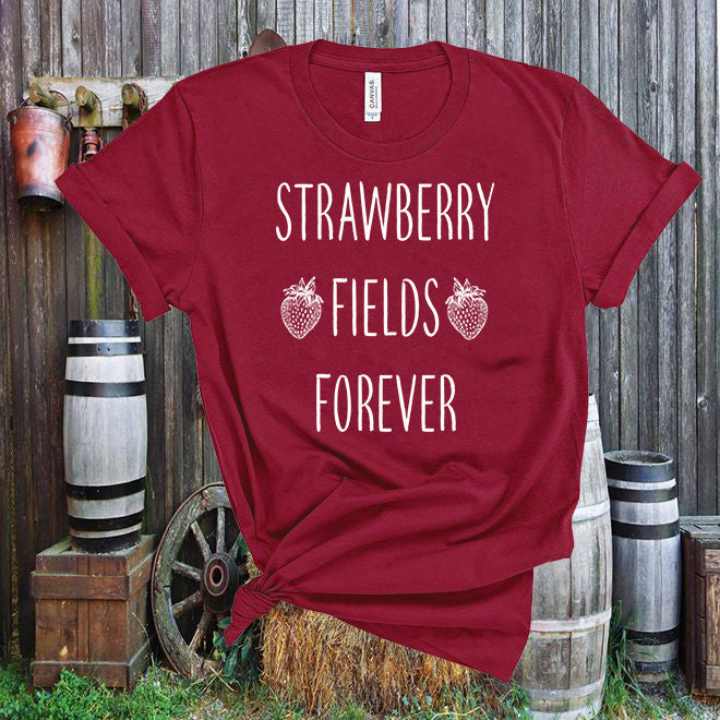 Red t-shirt with 'Strawberry Fields Forever' text in front of a rustic wooden background.
